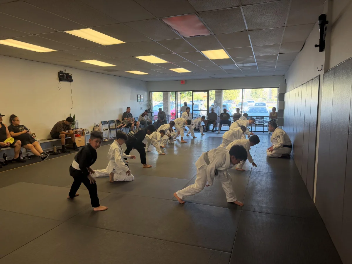 Kids jiu-jitsu class practicing escapes in age-grouped groups